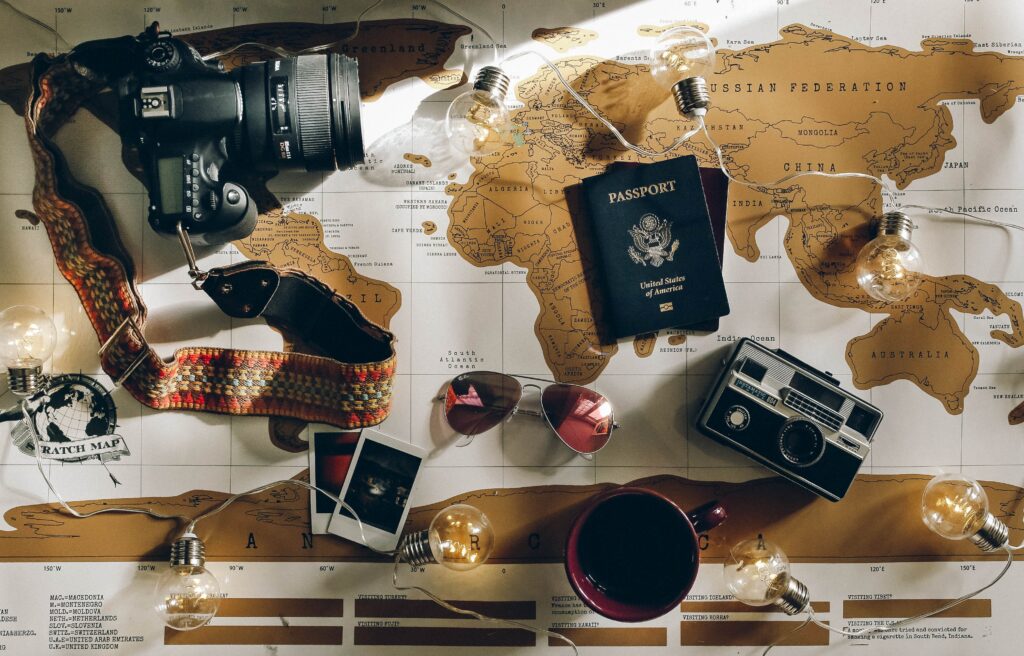 Map covered with items, including sunglasses, phone, cameras, passports, and more.