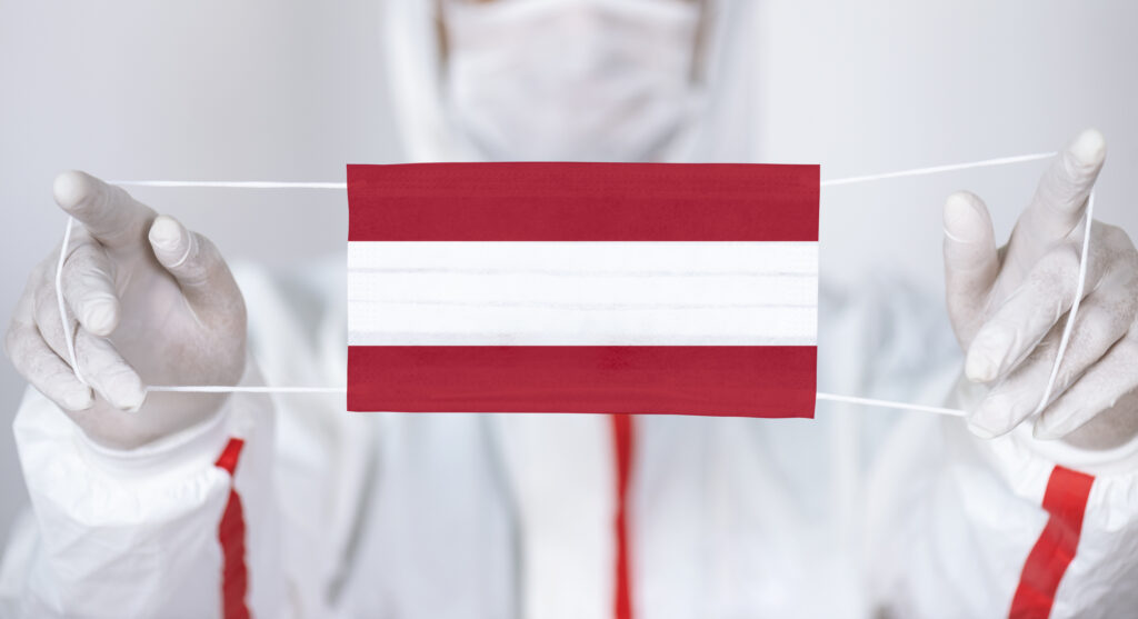 Healthcare personnel is holding Austrian Flag shaped surgical mask.