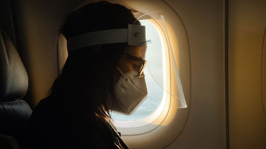 Woman on airplane with face shield and mask