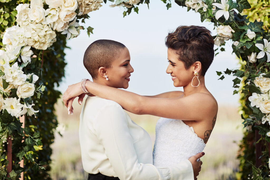 Lesbian couple standing at the alter getting married (Photo Credit: LumiNola/iStock)