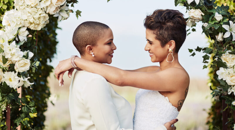 Lesbian couple standing at the alter getting married (Photo Credit: LumiNola/iStock)