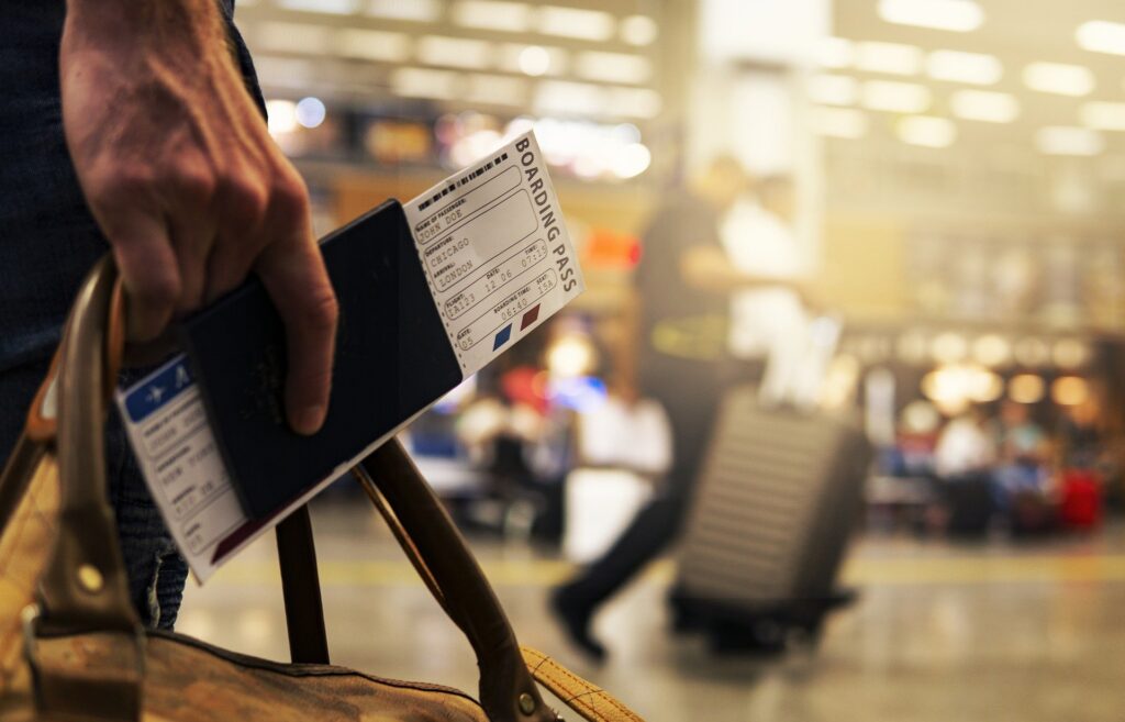 Close photo of man carrying passport and airplane ticket in an airport