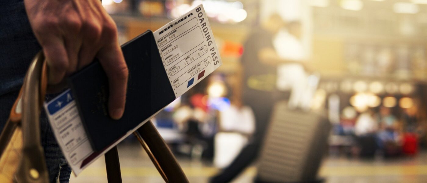 Close photo of man carrying passport and airplane ticket in an airport