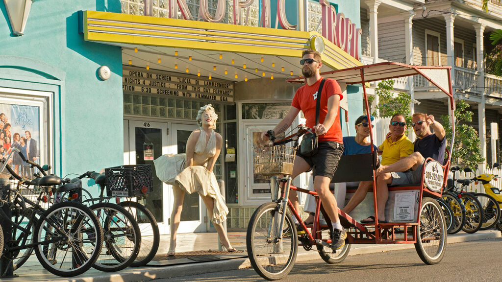 11 Ways to Enjoy the Florida Keys and Key West. In photo: A pedicab provides transportation past the Tropic Cinema Theater featuring a Seward Johnson metallic statue of Marilyn Monroe in a famous pose. (Photo Credit: Mike Freas/Florida Keys News Bureau)